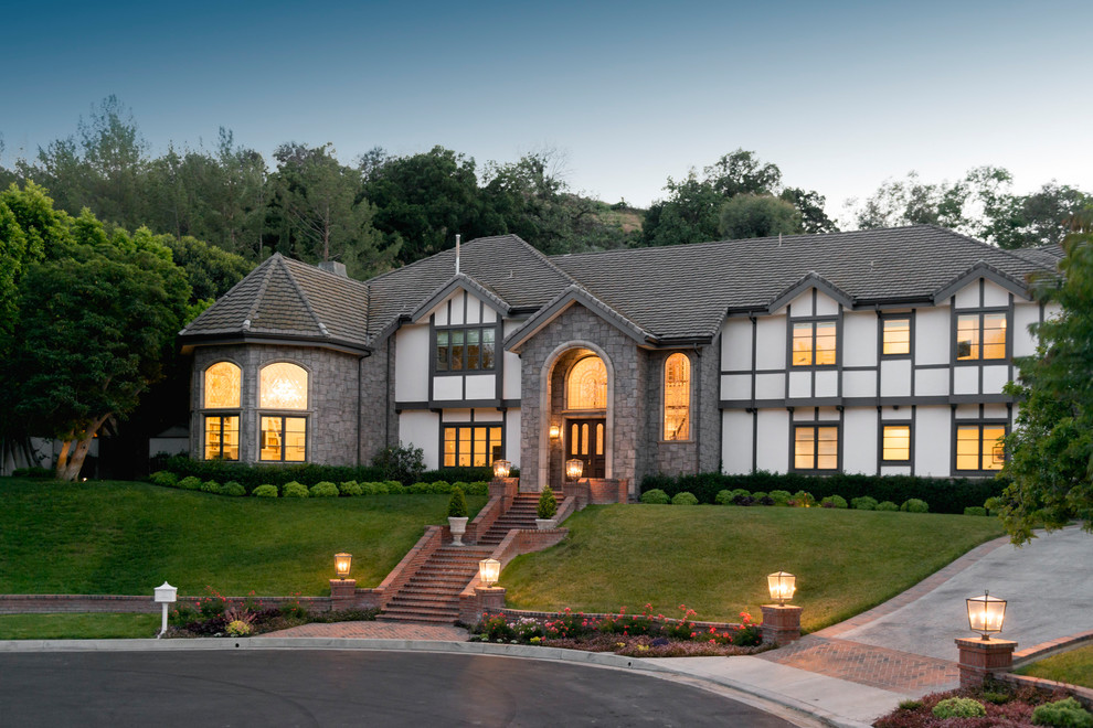 Large traditional two-storey stucco white house exterior in Los Angeles with a hip roof and a tile roof.