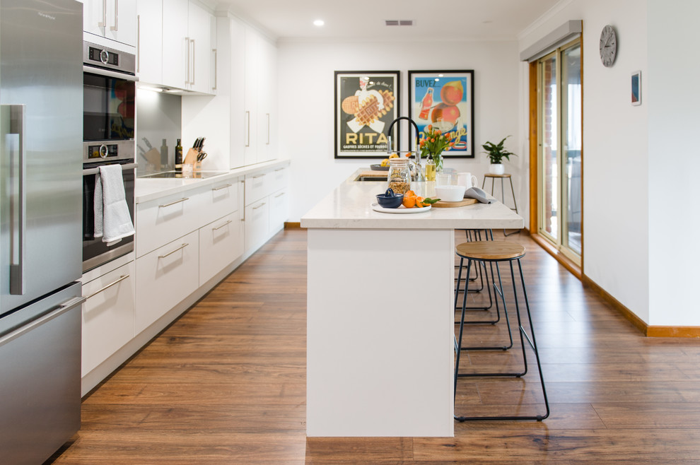 Large modern u-shaped kitchen pantry in Melbourne with a double-bowl sink, open cabinets, white cabinets, quartz benchtops, metallic splashback, glass sheet splashback, stainless steel appliances, medium hardwood floors, with island and beige benchtop.