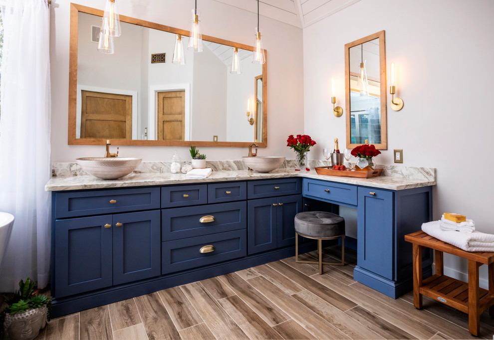 Transitional medium tone wood floor and brown floor freestanding bathtub photo in Atlanta with shaker cabinets, blue cabinets, white walls and a vessel sink