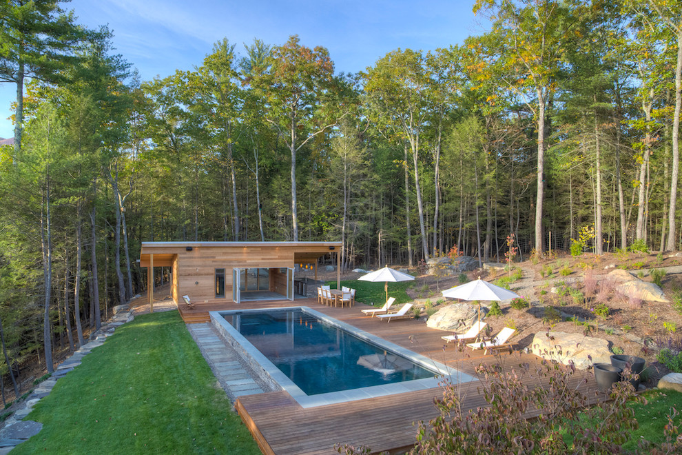 Inspiration for a mid-sized country side yard rectangular lap pool in New York with a pool house and decking.