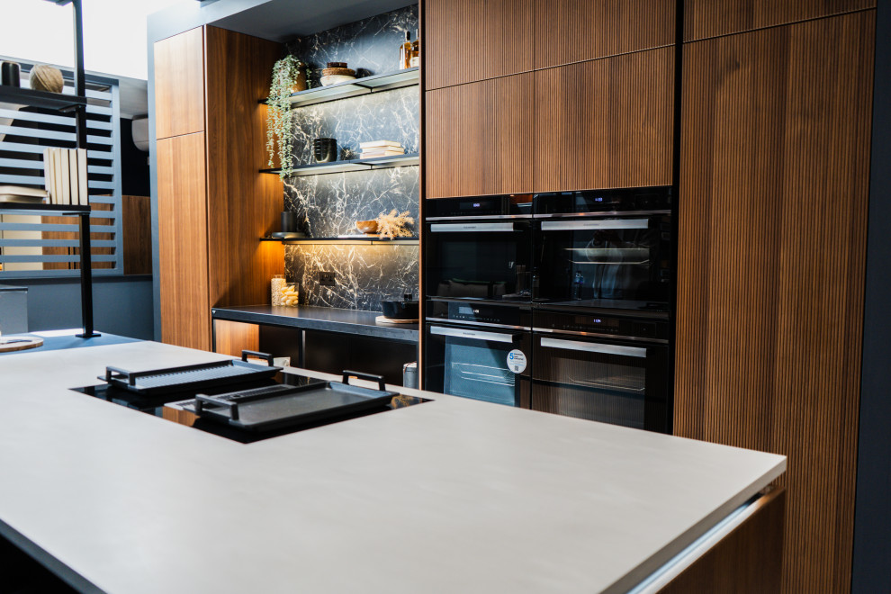 Inspiration for a medium sized modern l-shaped open plan kitchen in London with a built-in sink, glass-front cabinets, black cabinets, marble worktops, black splashback, stone slab splashback, black appliances, porcelain flooring, an island, grey floors and black worktops.