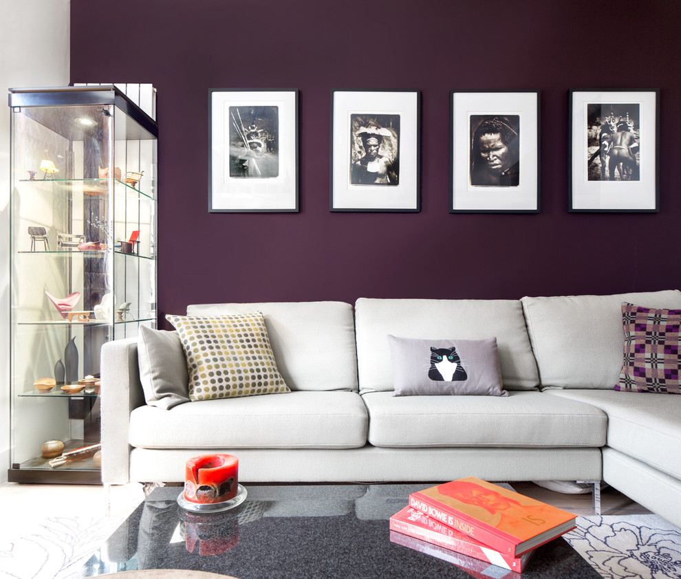 This is an example of a small contemporary open concept living room in London with light hardwood floors, a ribbon fireplace, a plaster fireplace surround, a wall-mounted tv, brown floor and purple walls.