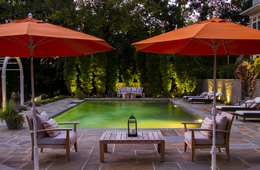 Photo of a mid-sized traditional backyard rectangular pool in New York with natural stone pavers.