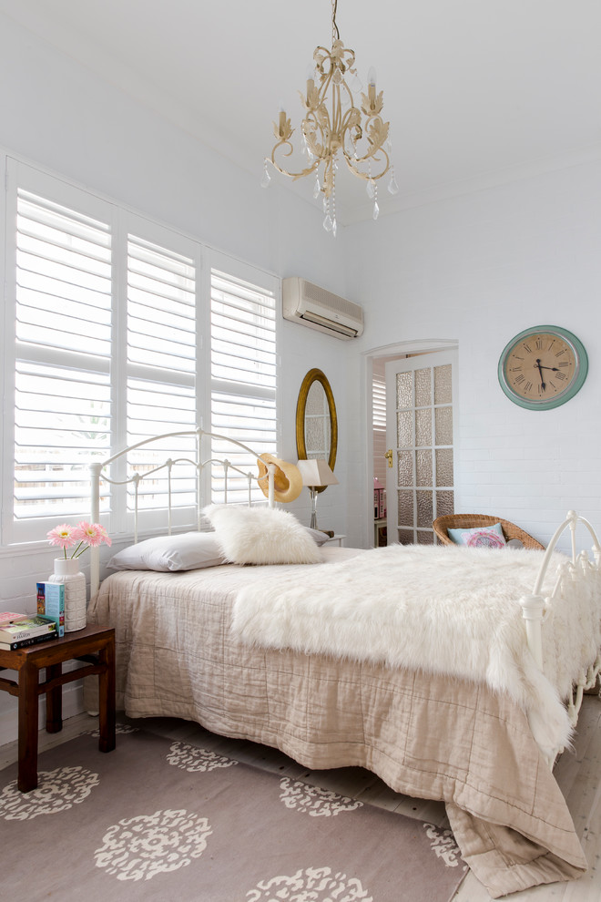 This is an example of a traditional bedroom in Sydney with white walls and light hardwood floors.