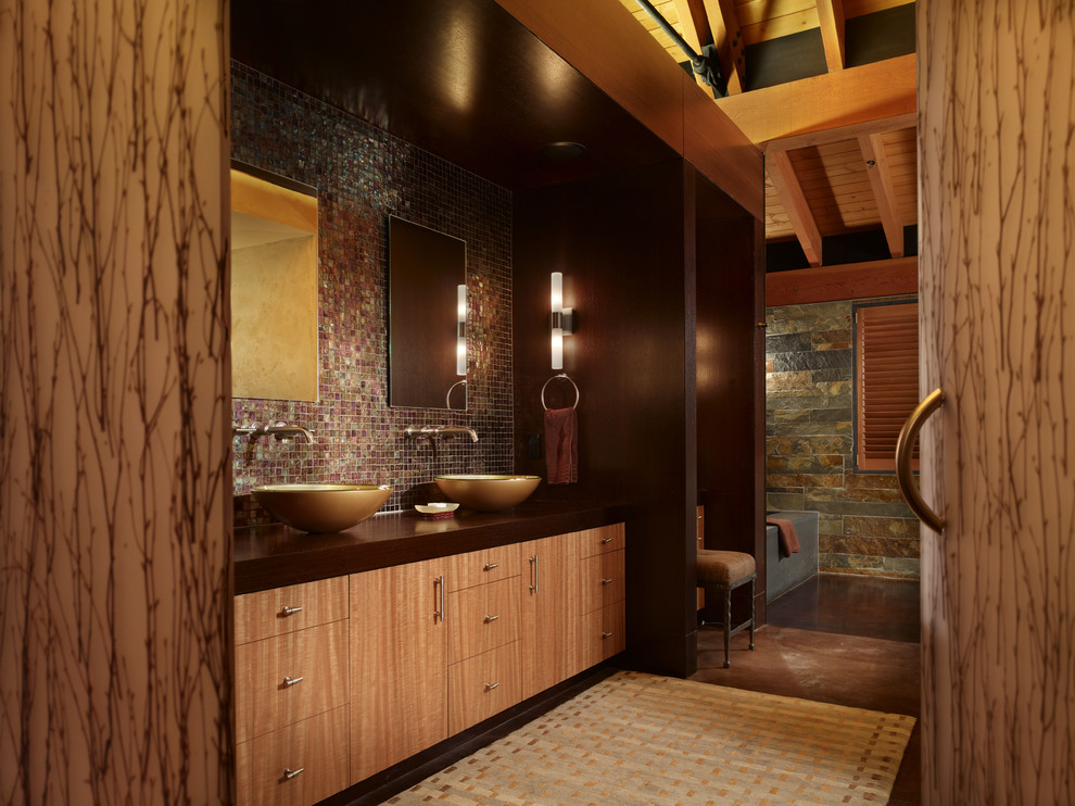 Photo of a large country master bathroom in Seattle with flat-panel cabinets, light wood cabinets, an alcove tub, brown tile, mosaic tile, multi-coloured walls, concrete floors, a vessel sink, wood benchtops and brown floor.