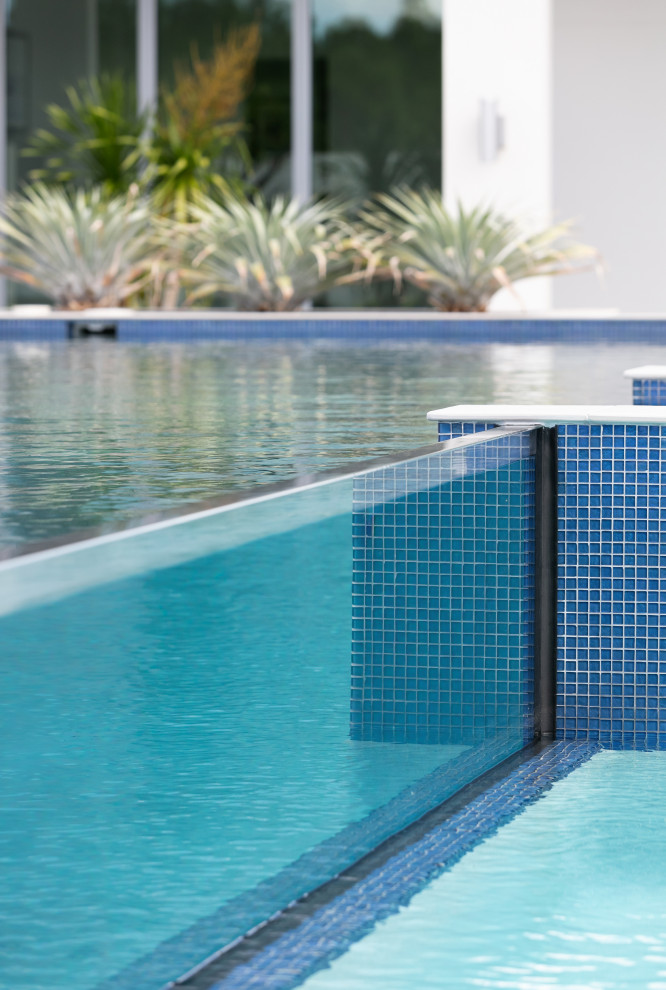 Esempio di un'ampia piscina monocorsia contemporanea personalizzata dietro casa con una vasca idromassaggio e piastrelle