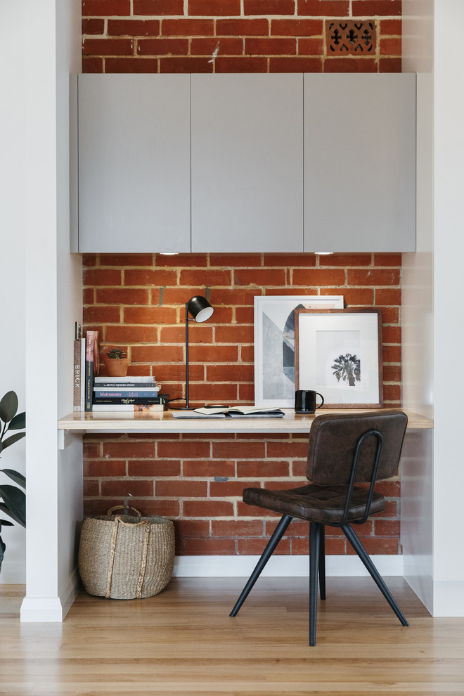 Small industrial study room in Adelaide with light hardwood floors and a built-in desk.