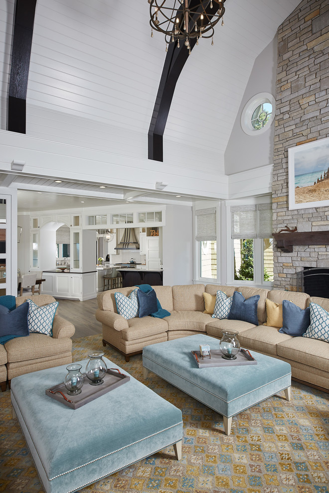 Photo of a large beach style open concept living room in Grand Rapids with grey walls, medium hardwood floors, a standard fireplace and a stone fireplace surround.