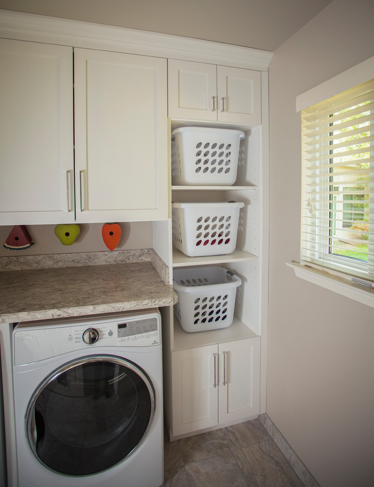 Small contemporary galley dedicated laundry room in Detroit with a farmhouse sink, white cabinets, granite benchtops, beige walls, a side-by-side washer and dryer, beige floor, ceramic floors and shaker cabinets.