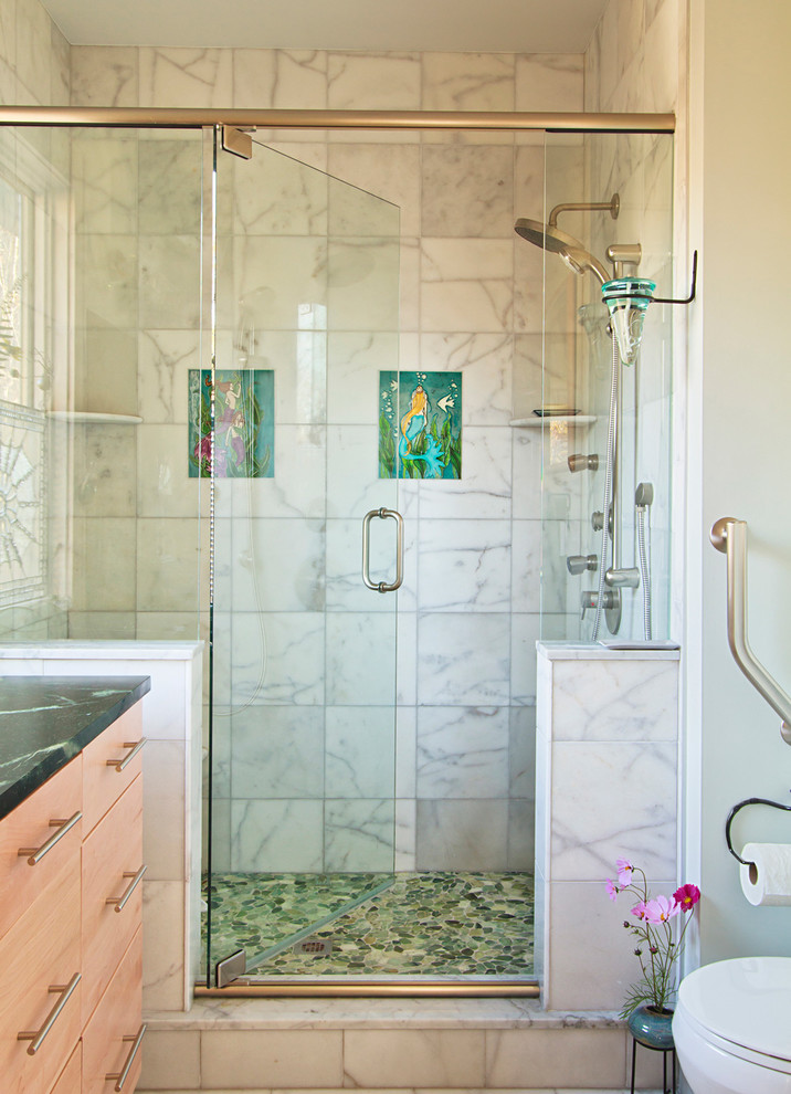 Photo of a small transitional 3/4 bathroom in Other with flat-panel cabinets, light wood cabinets, white tile, marble, pebble tile floors, soapstone benchtops, green floor and a hinged shower door.