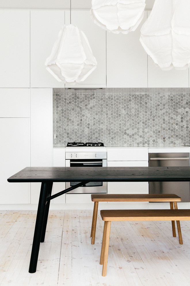Photo of a scandinavian single-wall eat-in kitchen in Sydney with grey splashback, stone tile splashback, black appliances and light hardwood floors.