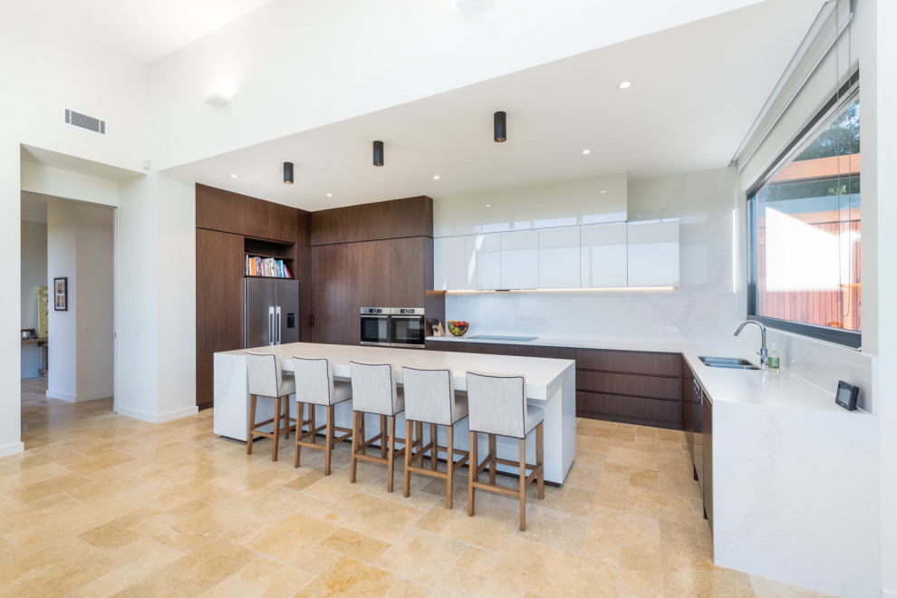 Photo of a large contemporary u-shaped open plan kitchen in Melbourne with an undermount sink, flat-panel cabinets, dark wood cabinets, quartz benchtops, white splashback, engineered quartz splashback, stainless steel appliances, cement tiles, with island, brown floor and white benchtop.