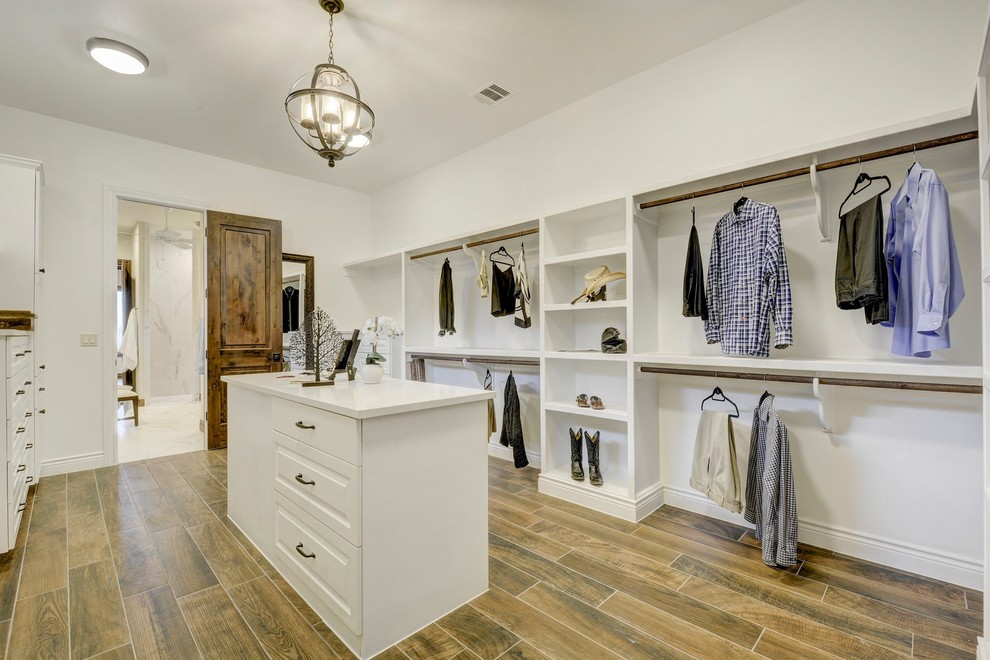 This is an example of a traditional gender-neutral dressing room in Austin with open cabinets, white cabinets and brown floor.