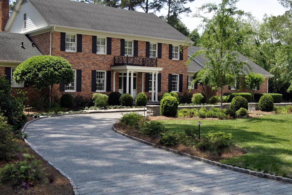 Large traditional three-storey brick red house exterior in Atlanta with a gable roof and a shingle roof.