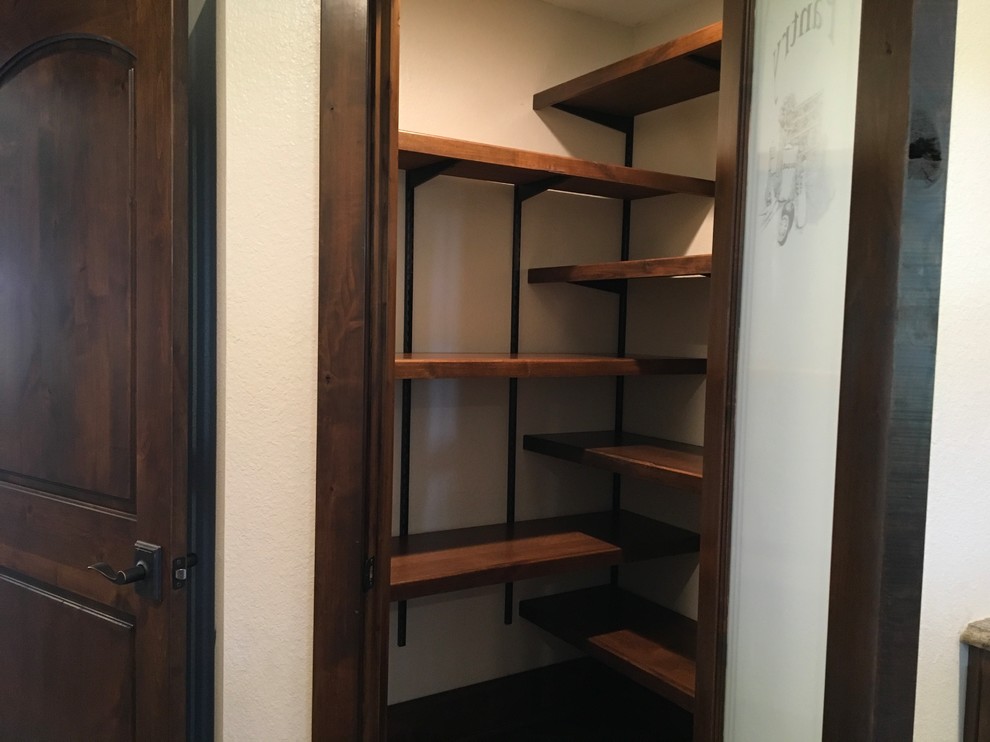 Small arts and crafts kitchen pantry in Houston with dark wood cabinets, dark hardwood floors and brown floor.