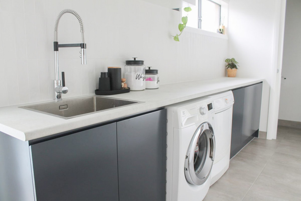 This is an example of a mid-sized single-wall utility room in Perth with a drop-in sink, raised-panel cabinets, white cabinets, copper benchtops, ceramic splashback, white walls, porcelain floors, a side-by-side washer and dryer, grey floor and multi-coloured benchtop.