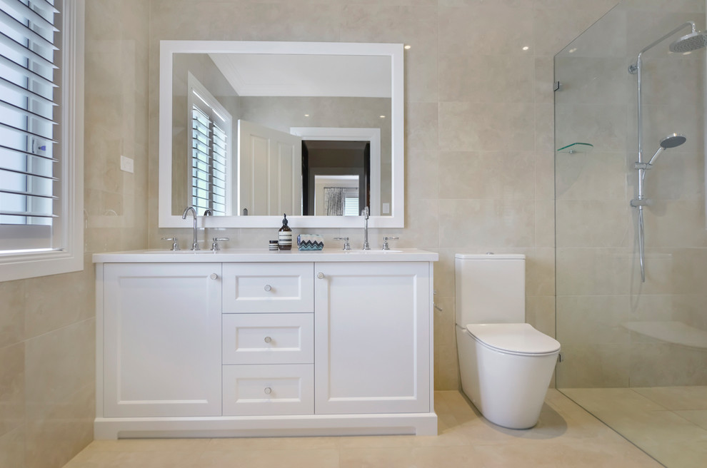 Photo of a large traditional 3/4 bathroom in Sydney with shaker cabinets, white cabinets, a curbless shower, a two-piece toilet, beige tile, an undermount sink, beige floor and white benchtops.