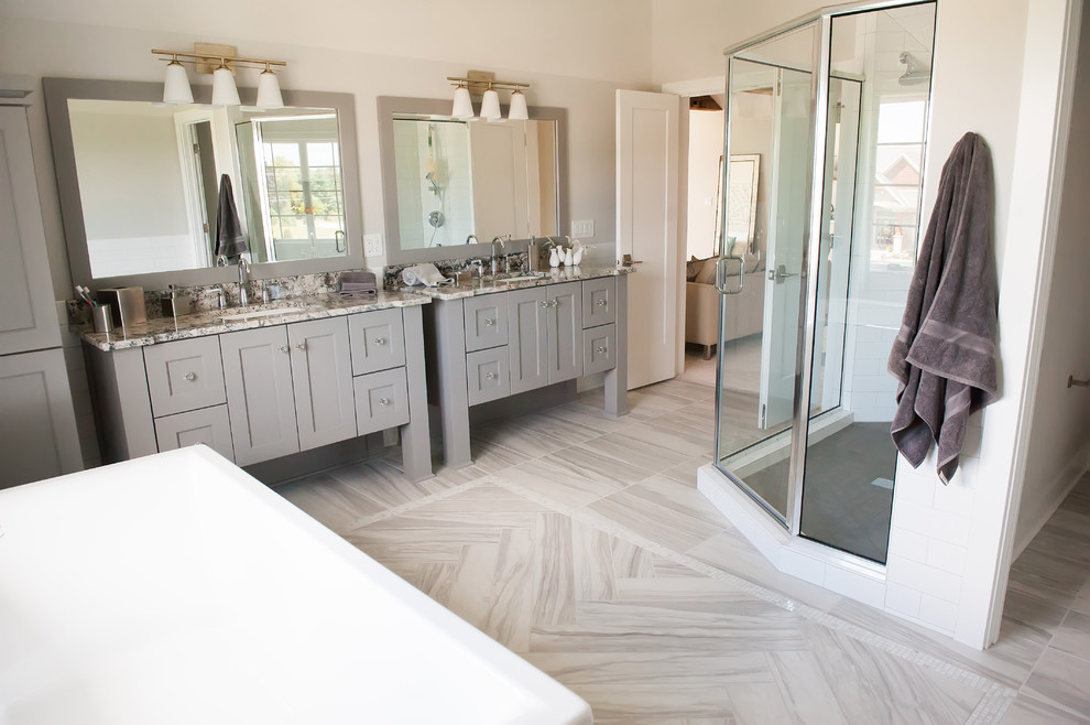 Inspiration for an expansive transitional master bathroom in Milwaukee with furniture-like cabinets, grey cabinets, a freestanding tub, a corner shower, white tile, subway tile, white walls, marble floors, an undermount sink, granite benchtops, grey floor, a hinged shower door and multi-coloured benchtops.