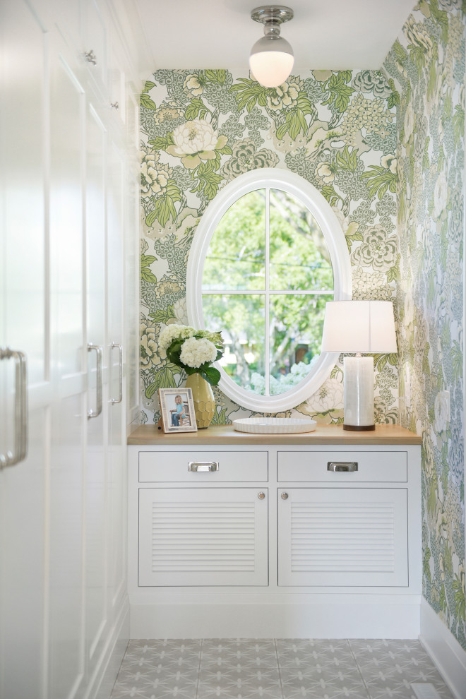 Photo of a beach style walk-in wardrobe in Minneapolis with louvered cabinets, white cabinets and grey floor.