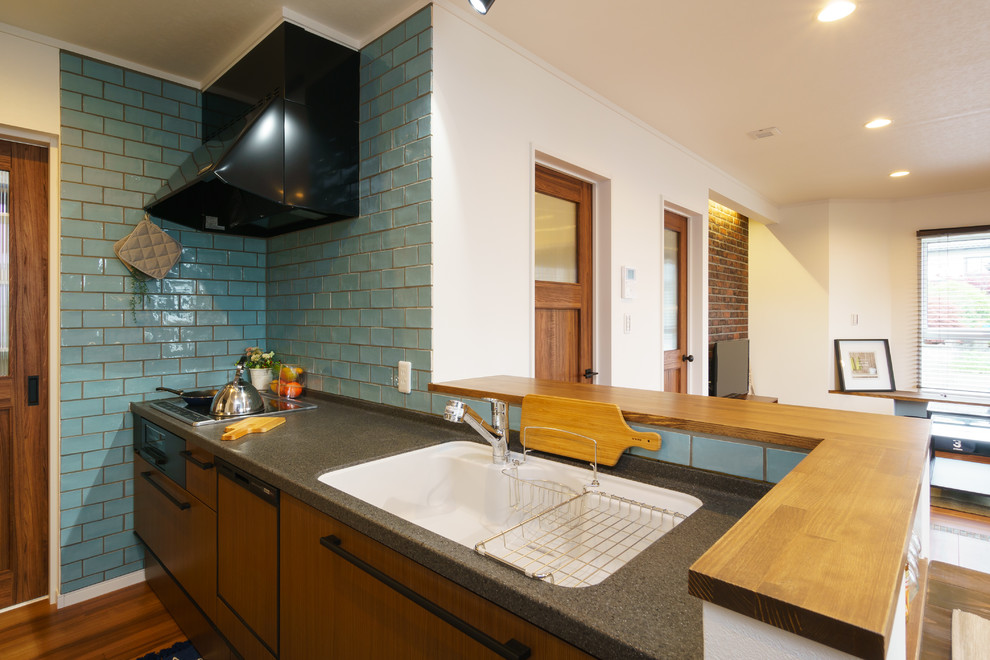 Beach style galley open plan kitchen in Other with a single-bowl sink, flat-panel cabinets, medium wood cabinets, blue splashback, medium hardwood floors, a peninsula and brown floor.
