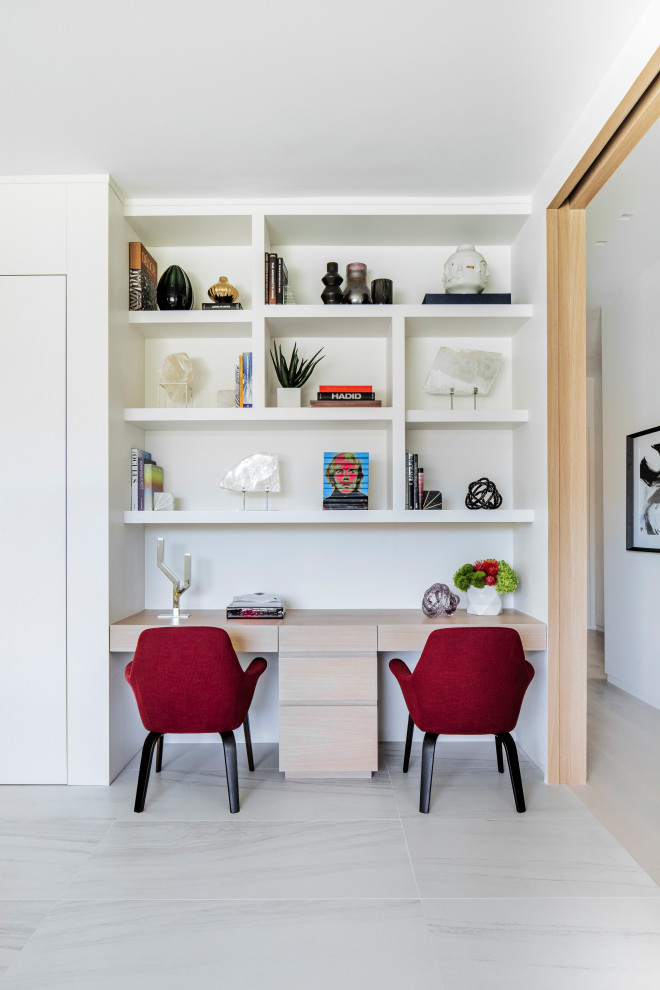 This is an example of a modern study room in Miami with white walls, marble floors, a built-in desk and white floor.