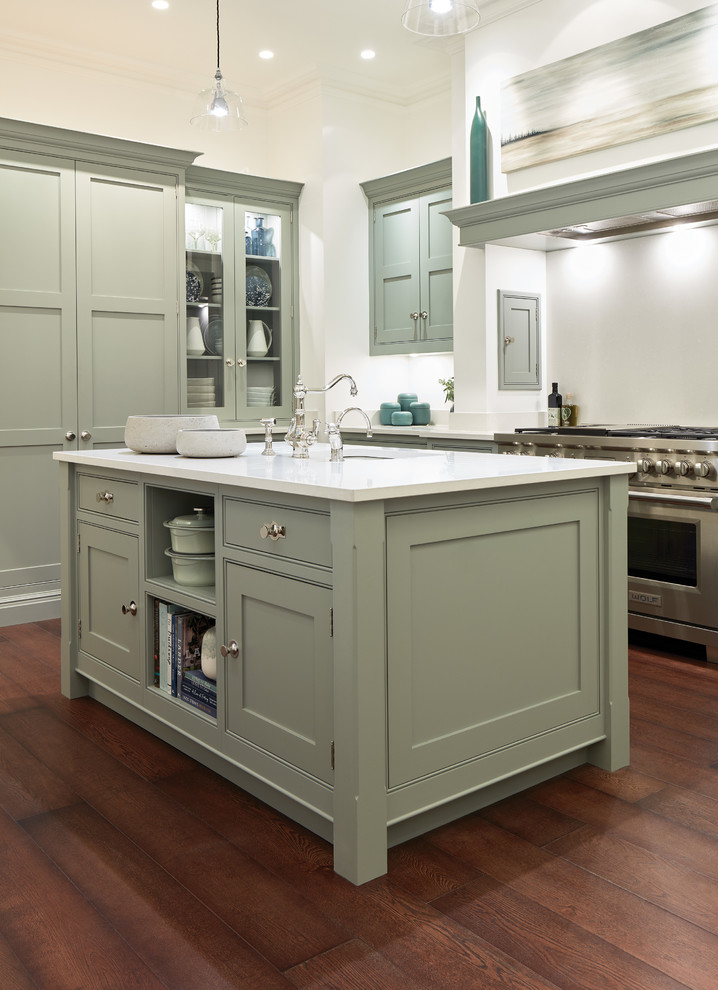 Photo of a large traditional l-shaped eat-in kitchen in London with shaker cabinets, green cabinets, quartzite benchtops, white splashback, stainless steel appliances, dark hardwood floors, with island, brown floor and white benchtop.