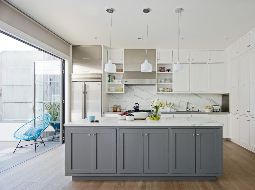 Photo of a transitional kitchen in San Francisco with shaker cabinets, white cabinets, white splashback, stainless steel appliances, medium hardwood floors and with island.