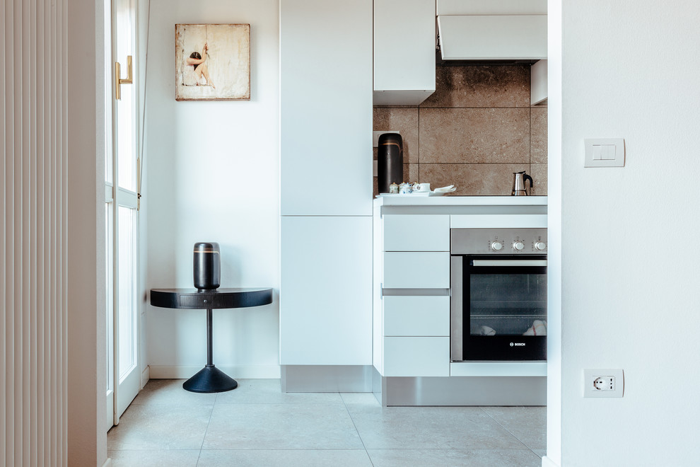 Inspiration for a small modern single-wall separate kitchen in Other with a single-bowl sink, flat-panel cabinets, white cabinets, solid surface benchtops, grey splashback, porcelain splashback, stainless steel appliances, porcelain floors, no island, grey floor and white benchtop.