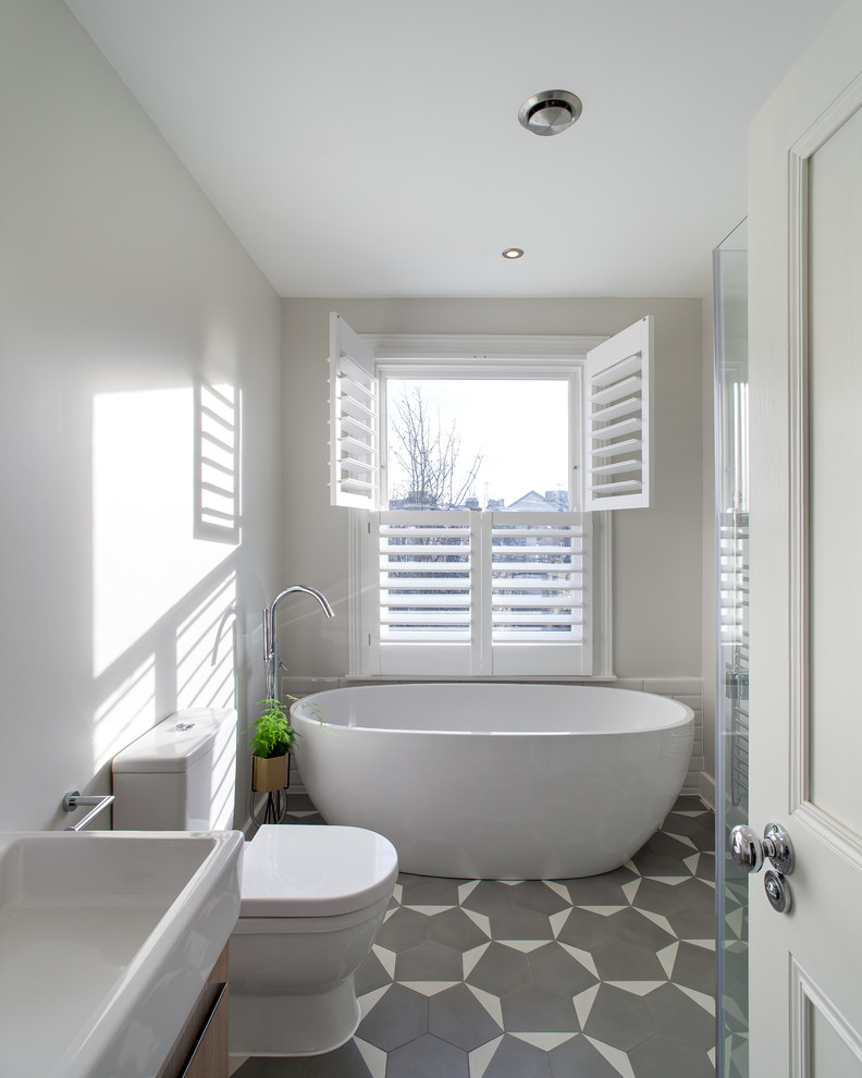 This is an example of a mid-sized contemporary kids wet room bathroom in London with a freestanding tub, white tile, ceramic tile, white walls, ceramic floors, a console sink, grey floor and an open shower.