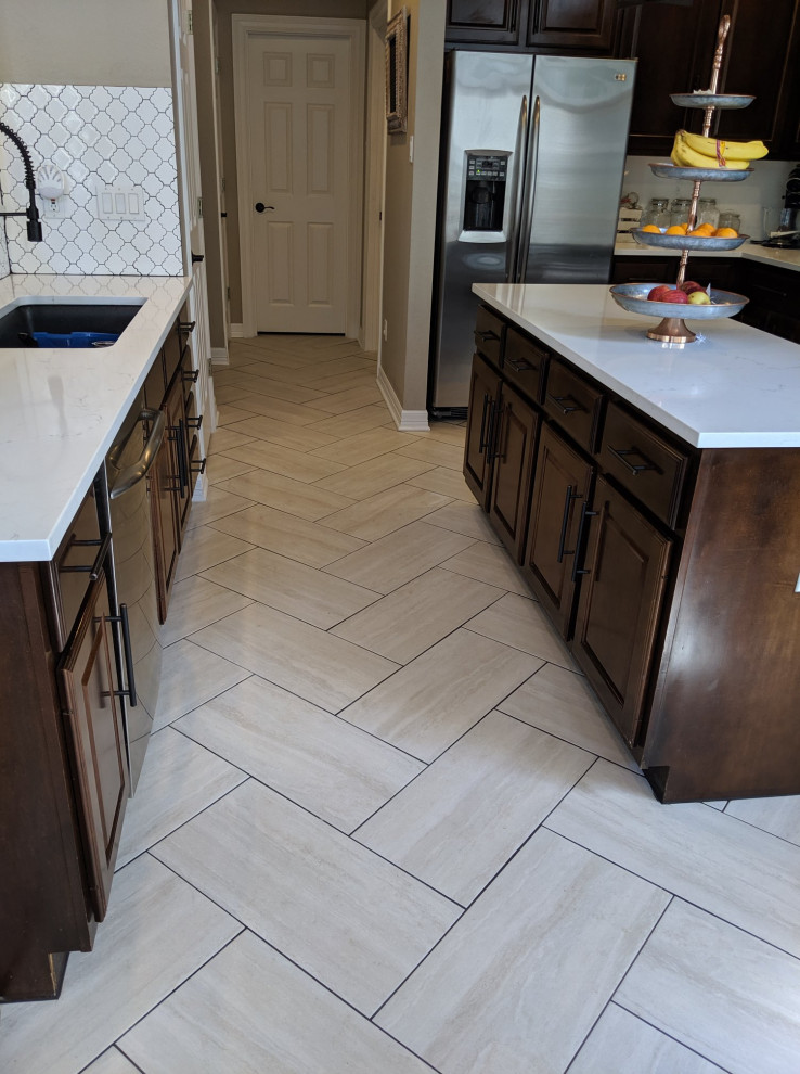 This is an example of a small traditional u-shaped eat-in kitchen in Austin with an undermount sink, recessed-panel cabinets, dark wood cabinets, quartz benchtops, white splashback, stainless steel appliances, ceramic floors, with island, beige floor and white benchtop.