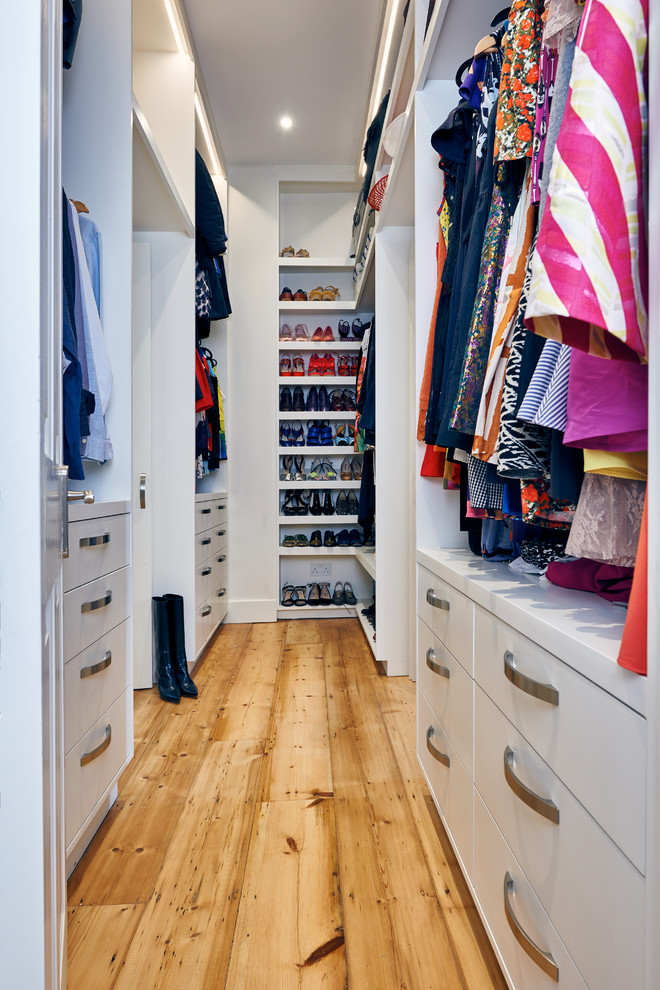 Inspiration for a large eclectic gender-neutral walk-in wardrobe in London with light hardwood floors and brown floor.