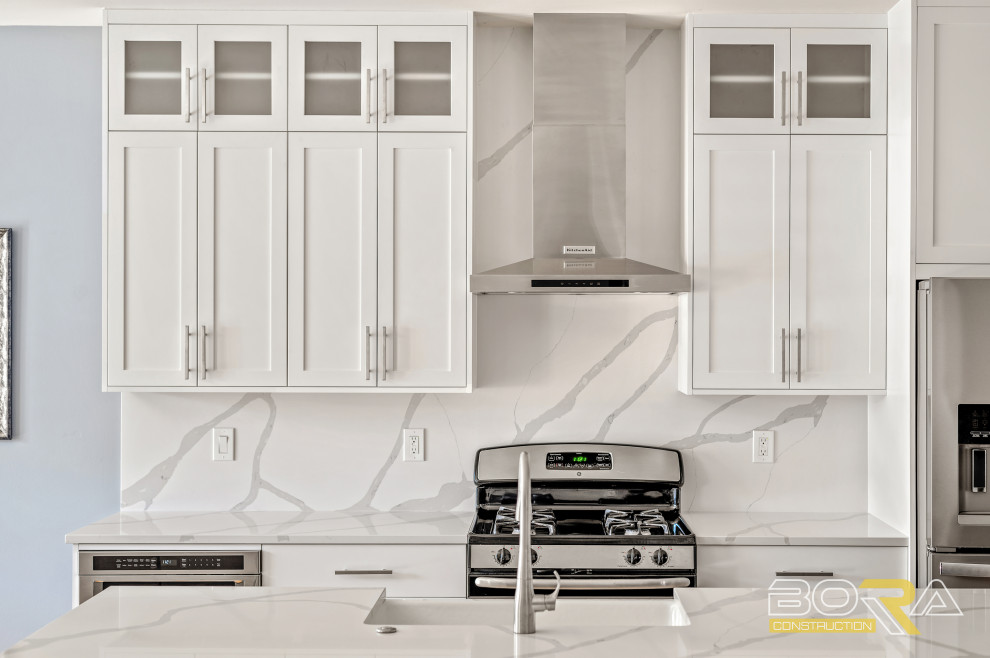 Inspiration for a mid-sized single-wall light wood floor and brown floor eat-in kitchen remodel in Seattle with a farmhouse sink, shaker cabinets, white cabinets, quartz countertops, white backsplash, quartz backsplash, stainless steel appliances, an island and white countertops