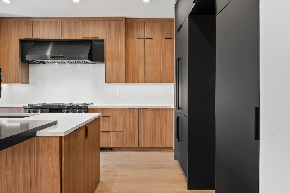 Expansive contemporary l-shaped open plan kitchen in Denver with a submerged sink, flat-panel cabinets, black cabinets, white splashback and an island.