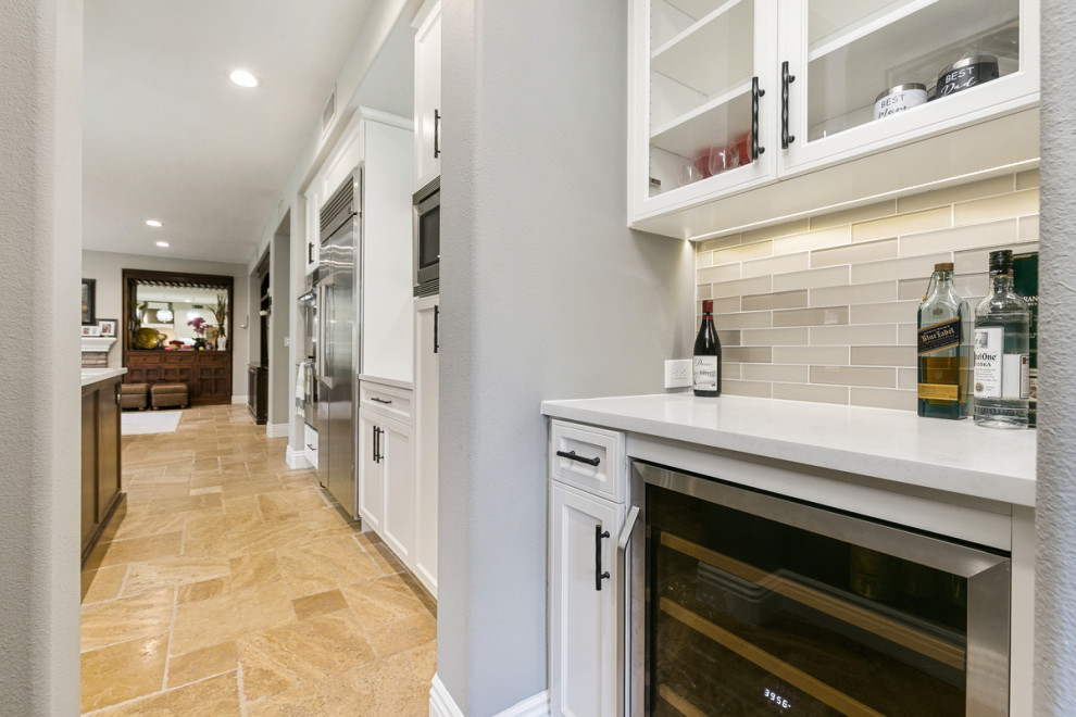 Open concept kitchen - huge transitional u-shaped travertine floor and beige floor open concept kitchen idea in Orange County with a single-bowl sink, shaker cabinets, white cabinets, quartz countertops, multicolored backsplash, stone tile backsplash, stainless steel appliances, an island and white countertops