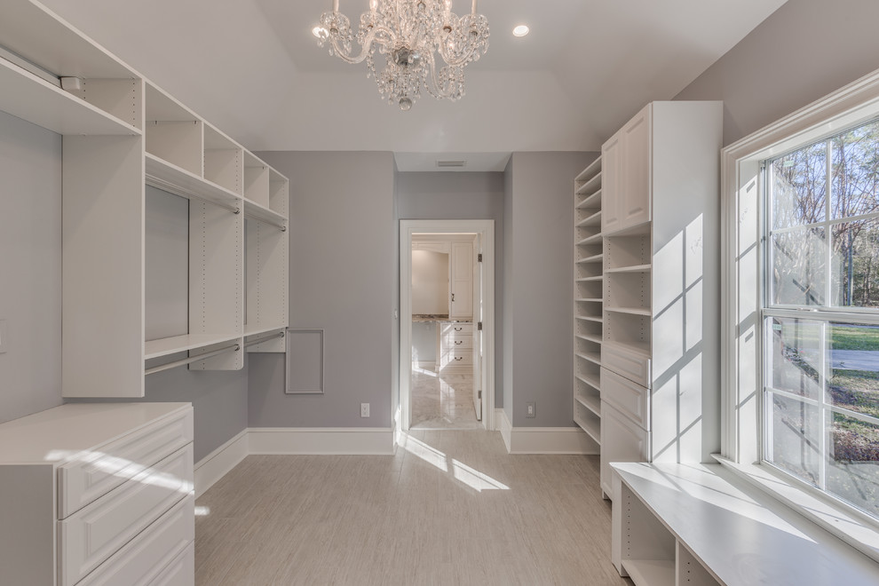 This is an example of a large traditional walk-in wardrobe in Jacksonville with white cabinets and porcelain floors.