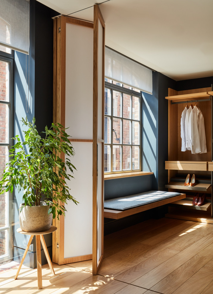 Imagen de armario vestidor de hombre minimalista pequeño con suelo de madera en tonos medios, armarios abiertos y puertas de armario de madera clara