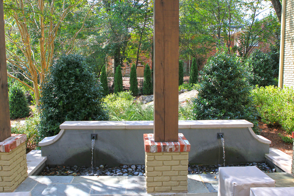 Example of a mid-sized transitional backyard stone patio fountain design in Birmingham with no cover