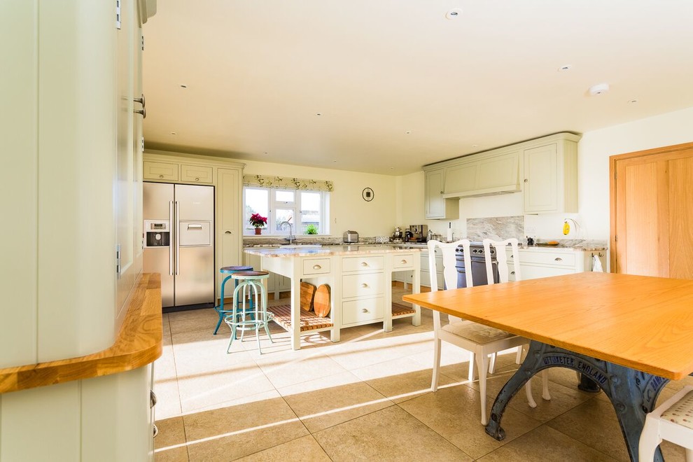 Photo of a large traditional l-shaped kitchen/diner in Oxfordshire with a double-bowl sink, shaker cabinets, green cabinets, granite worktops, grey splashback, stone tiled splashback, stainless steel appliances, limestone flooring and an island.