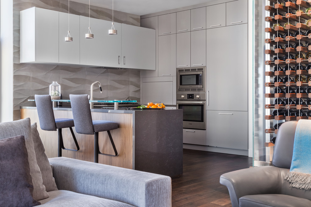 This is an example of a mid-sized contemporary open plan kitchen in San Francisco with flat-panel cabinets, grey cabinets, grey splashback, stainless steel appliances, dark hardwood floors, a peninsula and brown floor.