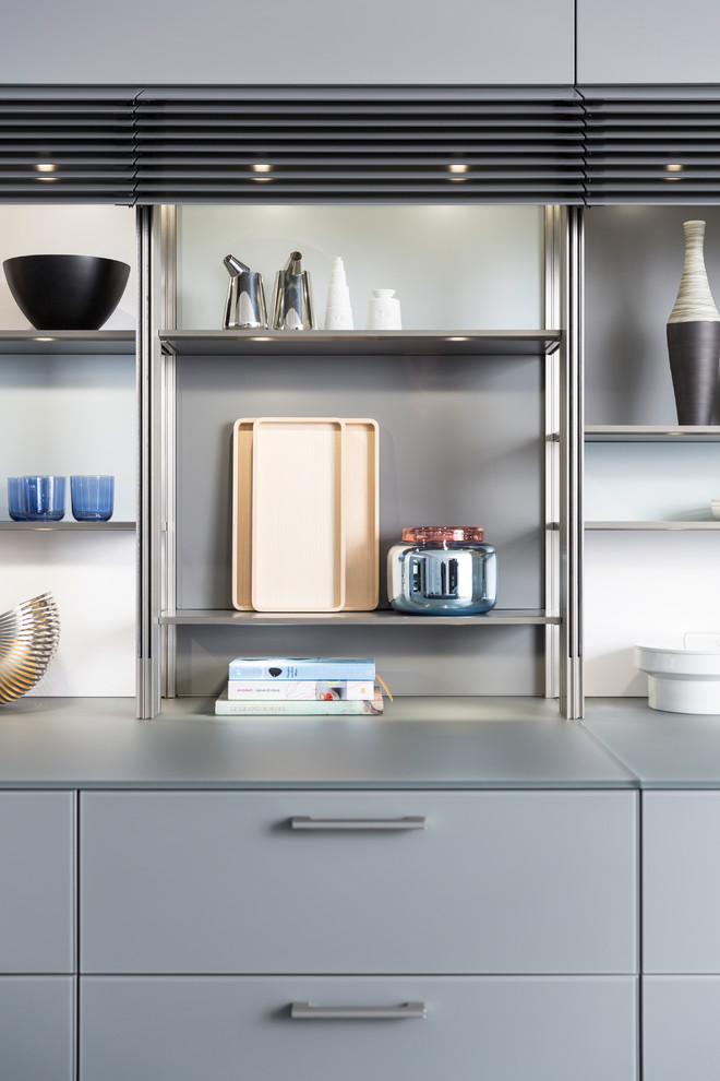 Large u-shaped dark wood floor eat-in kitchen photo in Orange County with an undermount sink, glass-front cabinets, gray cabinets, glass countertops, gray backsplash, stainless steel appliances and an island