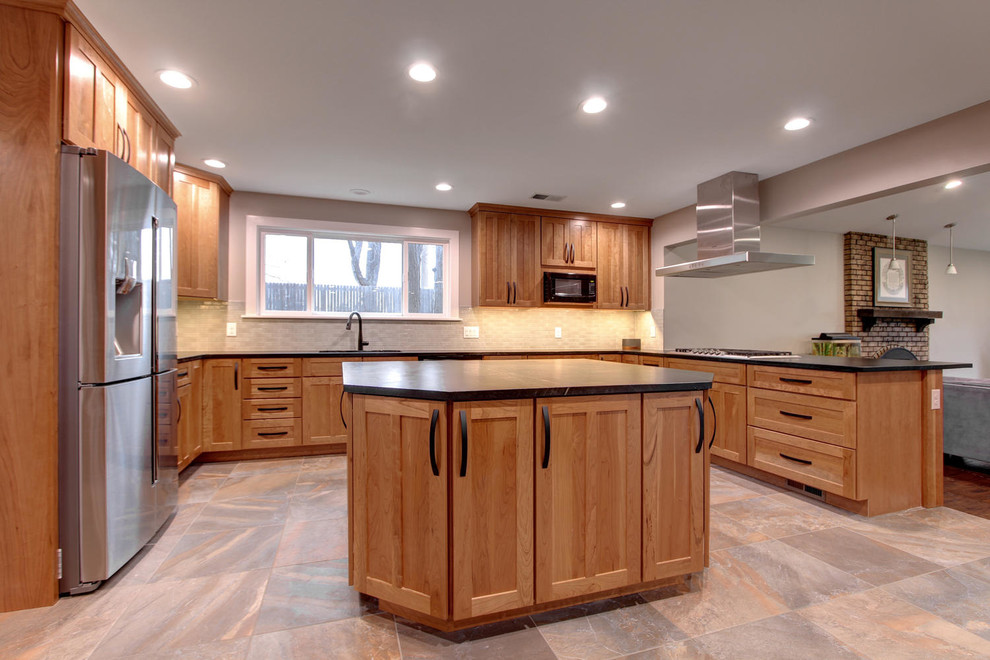 Inspiration for an arts and crafts u-shaped eat-in kitchen in Denver with a double-bowl sink, shaker cabinets, medium wood cabinets, soapstone benchtops, blue splashback, ceramic splashback, stainless steel appliances, porcelain floors and with island.