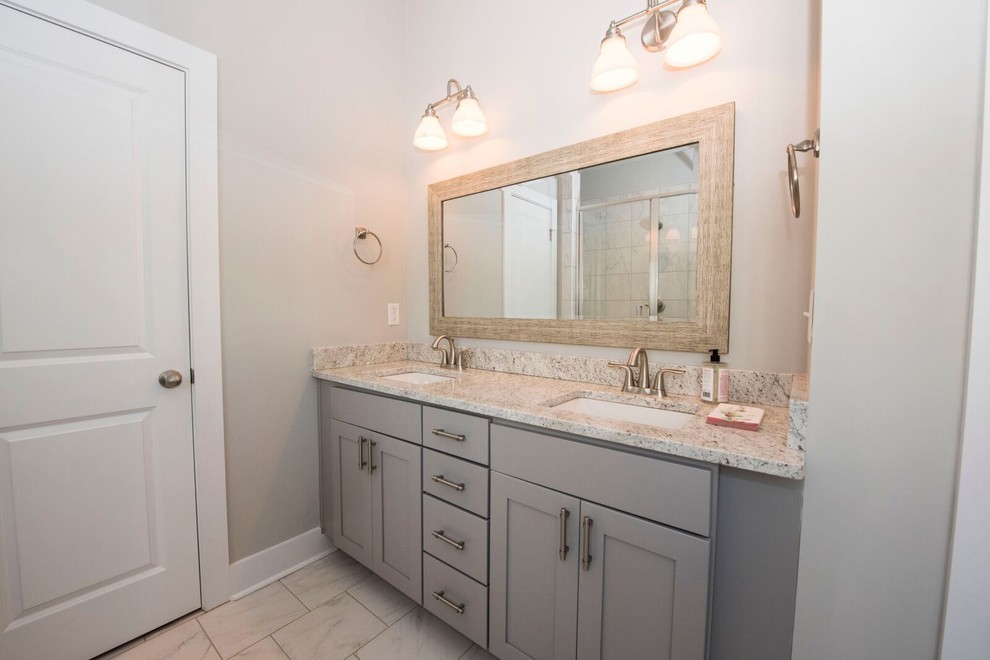 Photo of a mid-sized country master bathroom in Atlanta with recessed-panel cabinets, grey cabinets, a freestanding tub, stone slab, grey walls, porcelain floors, an undermount sink, granite benchtops, white floor and multi-coloured benchtops.