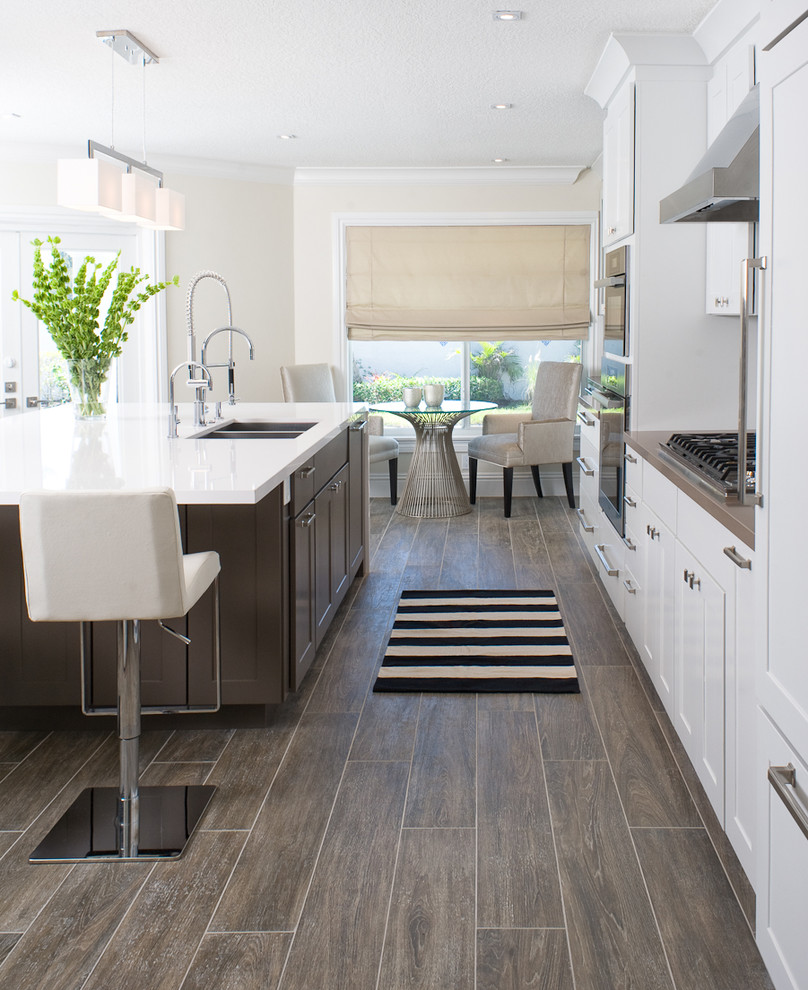 Inspiration for a transitional galley eat-in kitchen remodel in Miami with an undermount sink, shaker cabinets, white cabinets, stainless steel appliances and an island