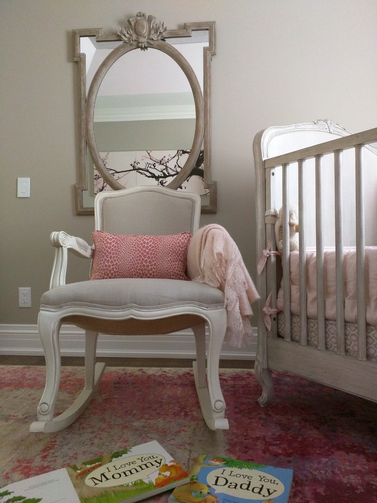 This is an example of a mid-sized traditional nursery for girls in Toronto with grey walls, medium hardwood floors and brown floor.