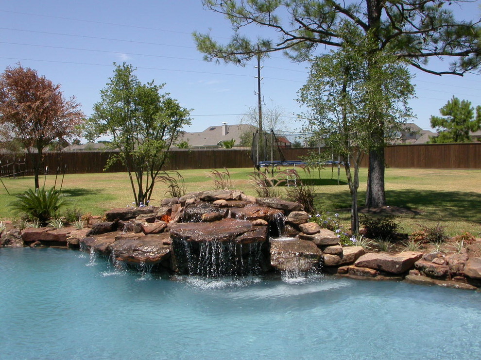 Inspiration for a large traditional backyard custom-shaped pool in Houston with a water feature and gravel.