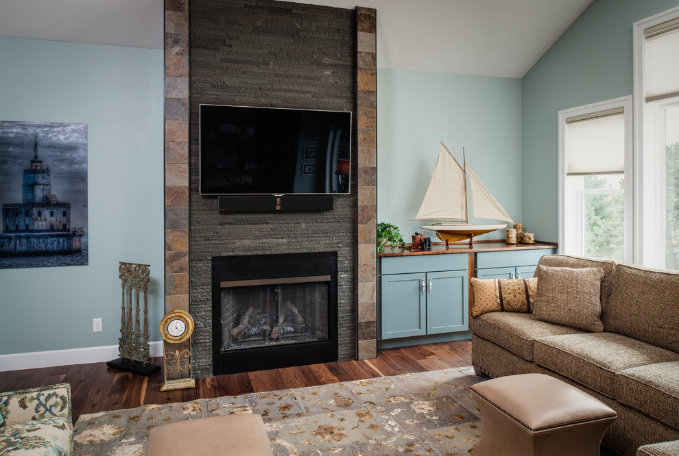 Photo of a mid-sized transitional open concept family room in Other with blue walls, medium hardwood floors, a standard fireplace, a tile fireplace surround and a wall-mounted tv.