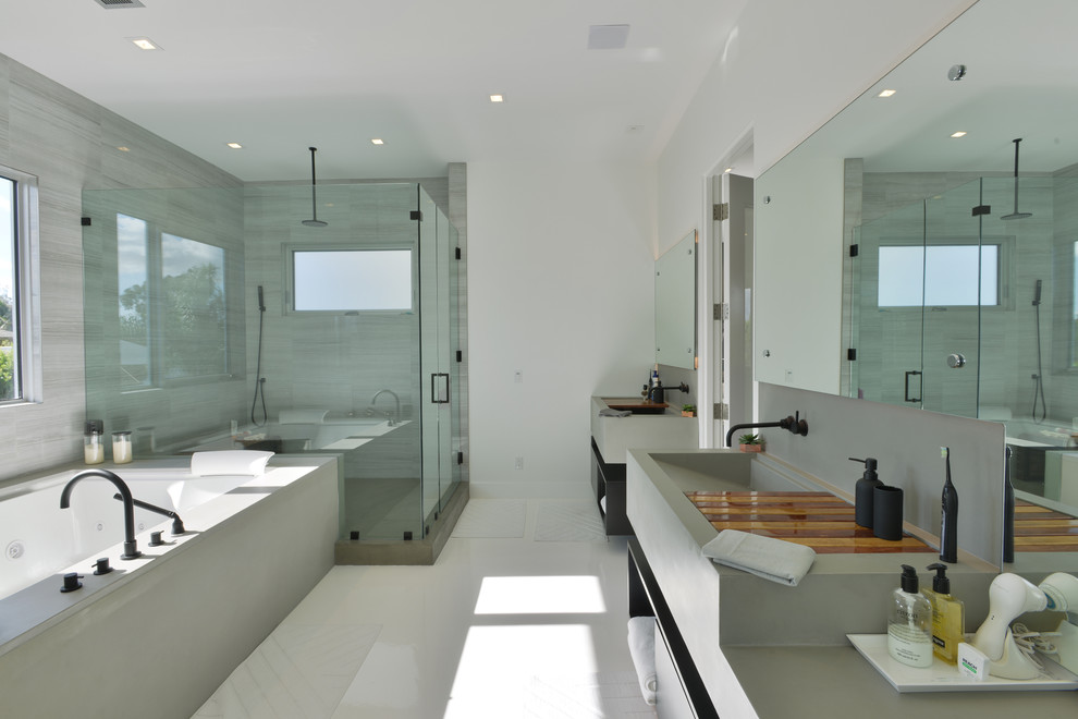 Large modern master bathroom in Los Angeles with open cabinets, black cabinets, a hot tub, an alcove shower, grey walls, a trough sink, solid surface benchtops, gray tile, porcelain tile, porcelain floors, white floor and a hinged shower door.