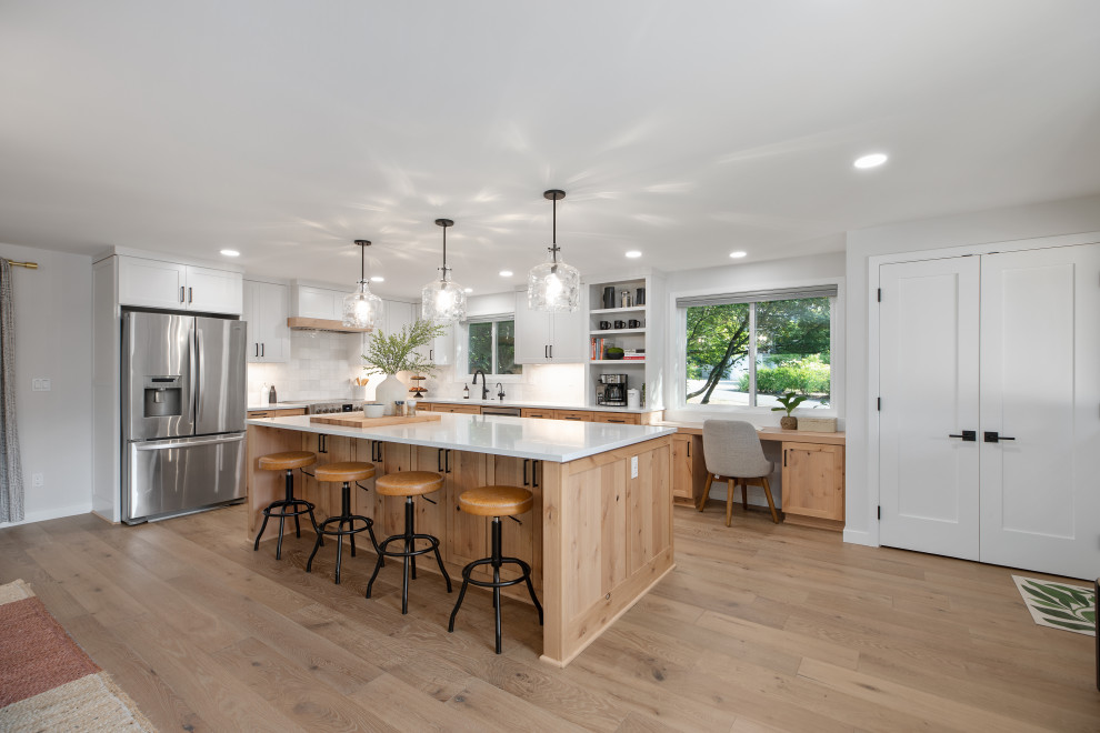 Design ideas for an expansive modern u-shaped eat-in kitchen in Portland with a drop-in sink, shaker cabinets, white cabinets, quartz benchtops, white splashback, ceramic splashback, stainless steel appliances, vinyl floors, with island, beige floor and white benchtop.
