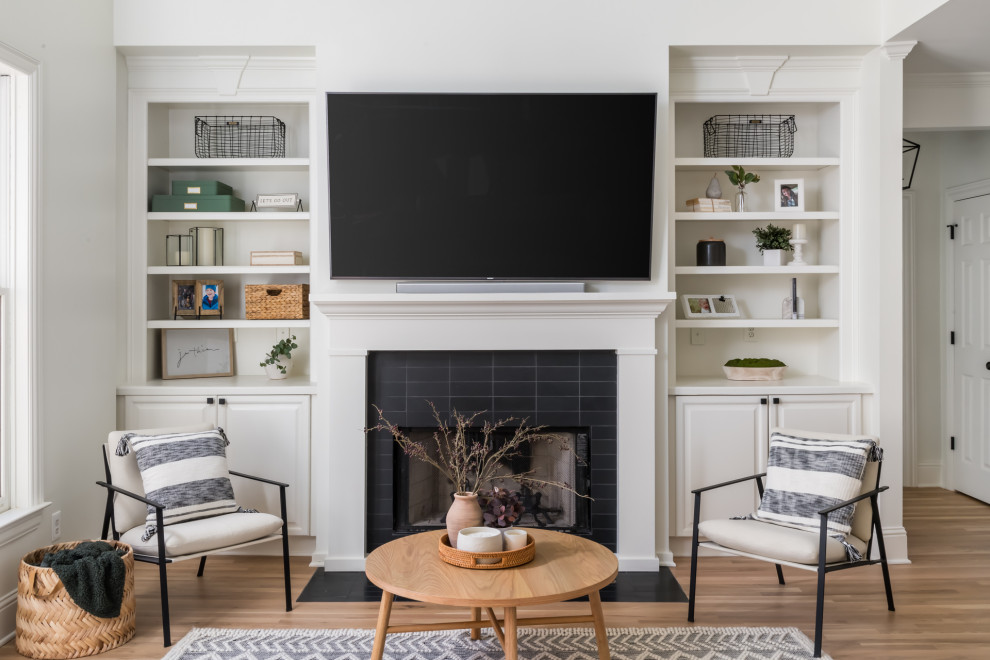 Inspiration for a large transitional loft-style light wood floor and black floor family room library remodel in Atlanta with white walls, a standard fireplace, a tile fireplace and a wall-mounted tv