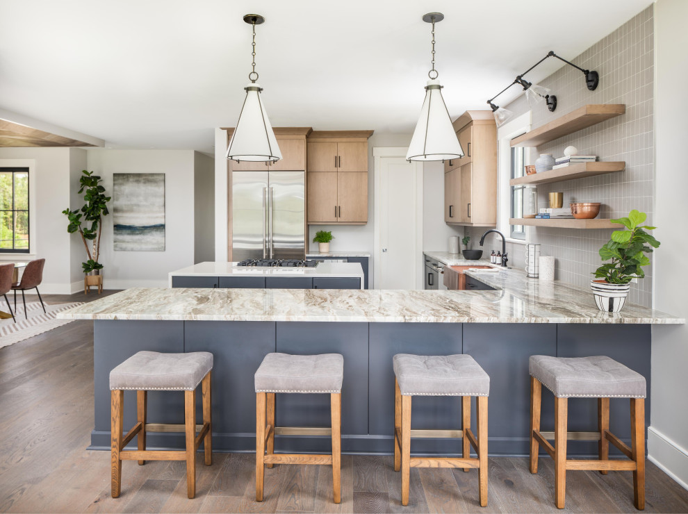 This is an example of a beach style u-shaped kitchen in Charleston with a farmhouse sink, flat-panel cabinets, light wood cabinets, grey splashback, stainless steel appliances, dark hardwood floors, multi-coloured benchtop and with island.